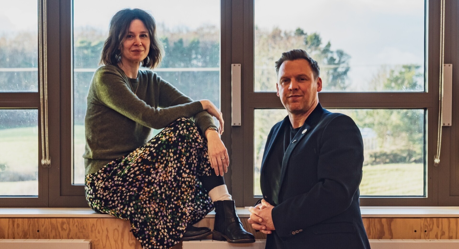 Kate Wasserberg (Artistic Director) and Liam Evans-Ford (Executive Director) posed in front of a window.