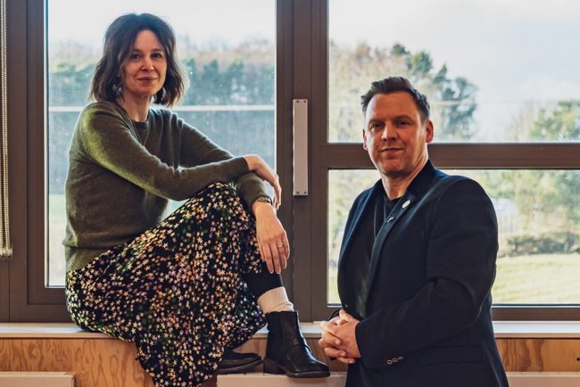Kate Wasserberg (Artistic Director) and Liam Evans-Ford (Executive Director) posed in front of a window.