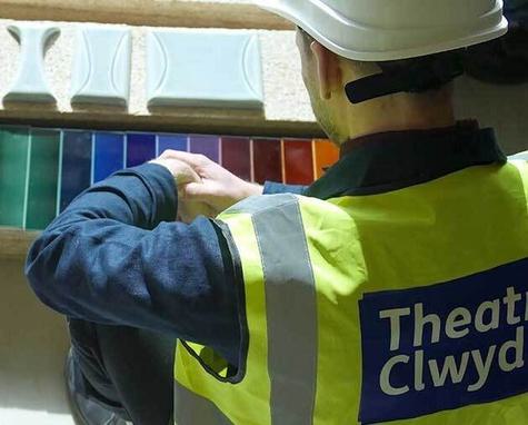 A man looking down at a range of brightly coloured tiles