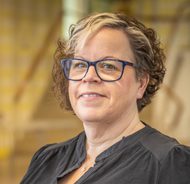 Headshot of Janine Dwan. White woman with brown and blonde hair, wearing black framed glasses.