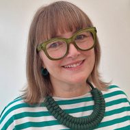 Headshot of Sarah Jones. Blonde haired white woman, wearing green framed glasses.